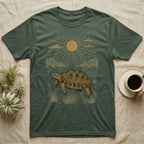 Russian Tortoise Home Range T-Shirt in Military Green — Woodcut-style illustration of a Russian tortoise walking across gravelly steppe under a full sun with dry hills behind, no on-shirt text.
