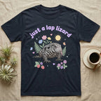 Argentine Tegu Baby T-Shirt in Navy — Black-and-white Argentine tegu with forked tongue among pastel flowers under puffy lavender text "just a lap lizard".