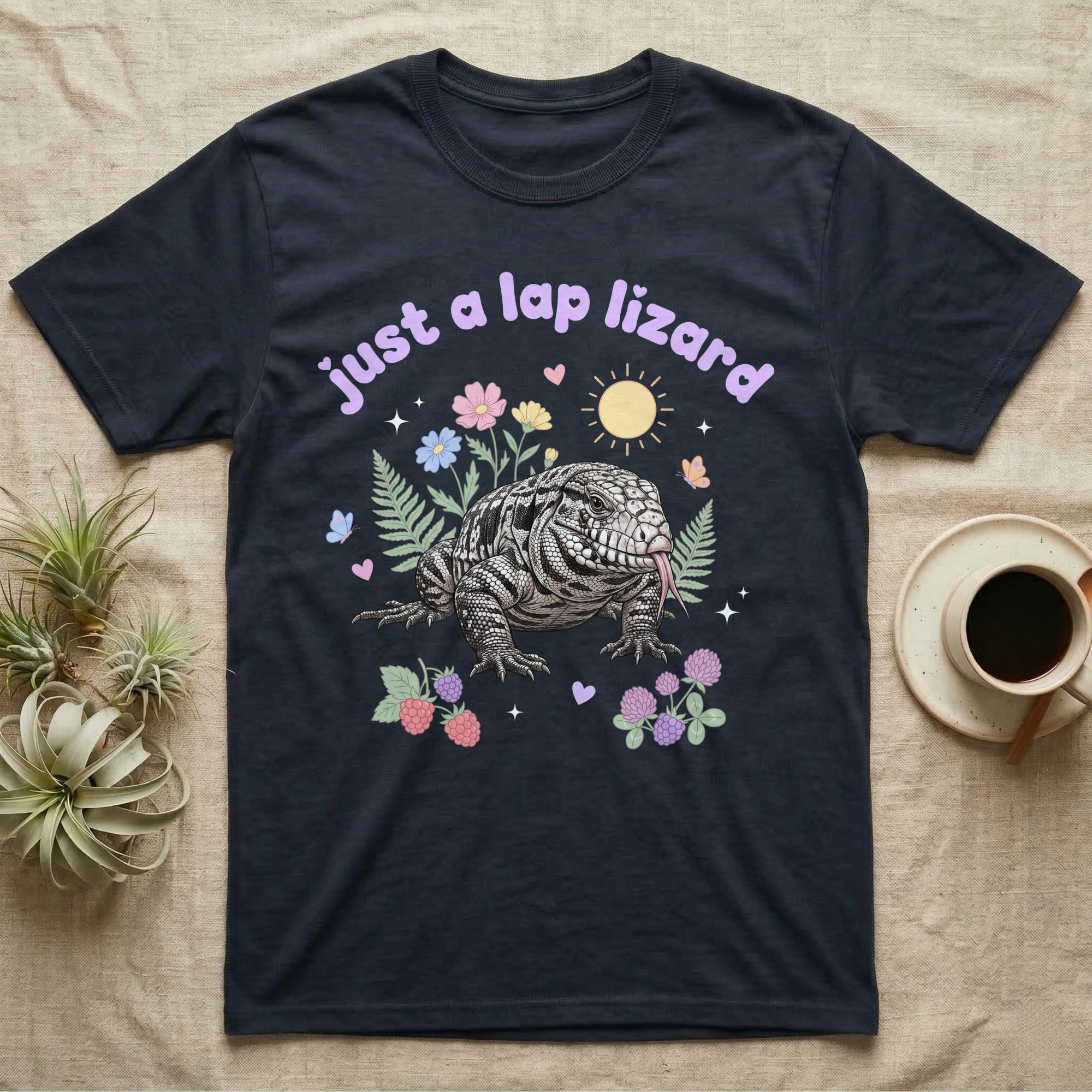 Argentine Tegu Baby T-Shirt in Navy — Black-and-white Argentine tegu with forked tongue among pastel flowers under puffy lavender text "just a lap lizard".
