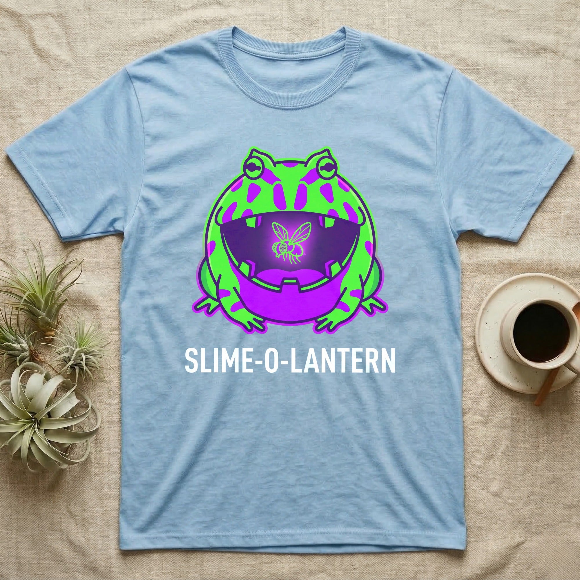 Pacman Frog Slime-O-Lantern T-Shirt in Light Blue — Neon pop-art Pacman frog shaped like a jack-o'-lantern with a lit fly in its mouth, "Slime-O-Lantern."