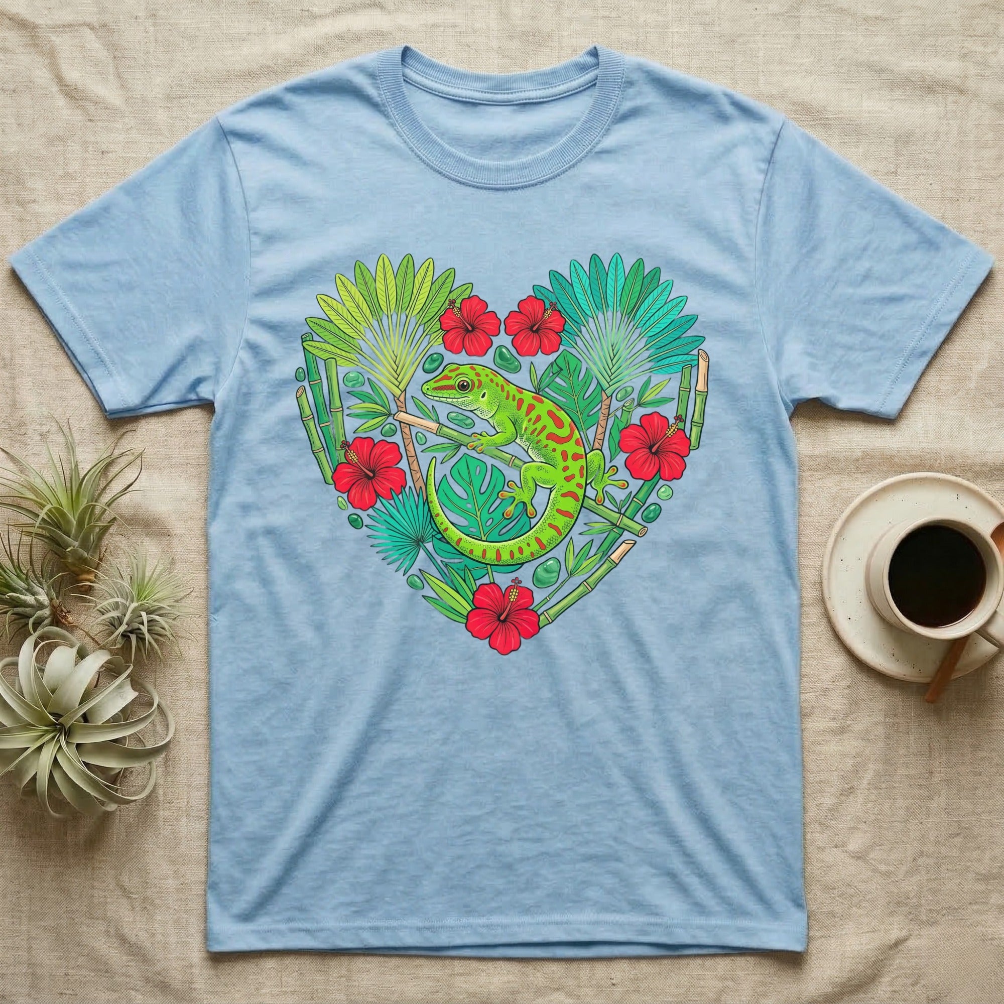Light blue t-shirt with a green gecko and tropical plants in a heart shape.
