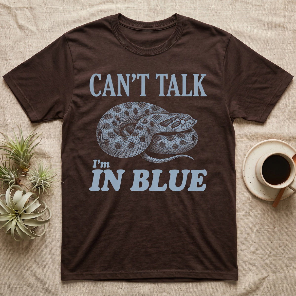 Hognose In Blue T-Shirt in Dark Chocolate — Milky blue engraved coiled western hognose with a cloudy pre-shed eye on black under the words CAN'T TALK, I'm IN BLUE
