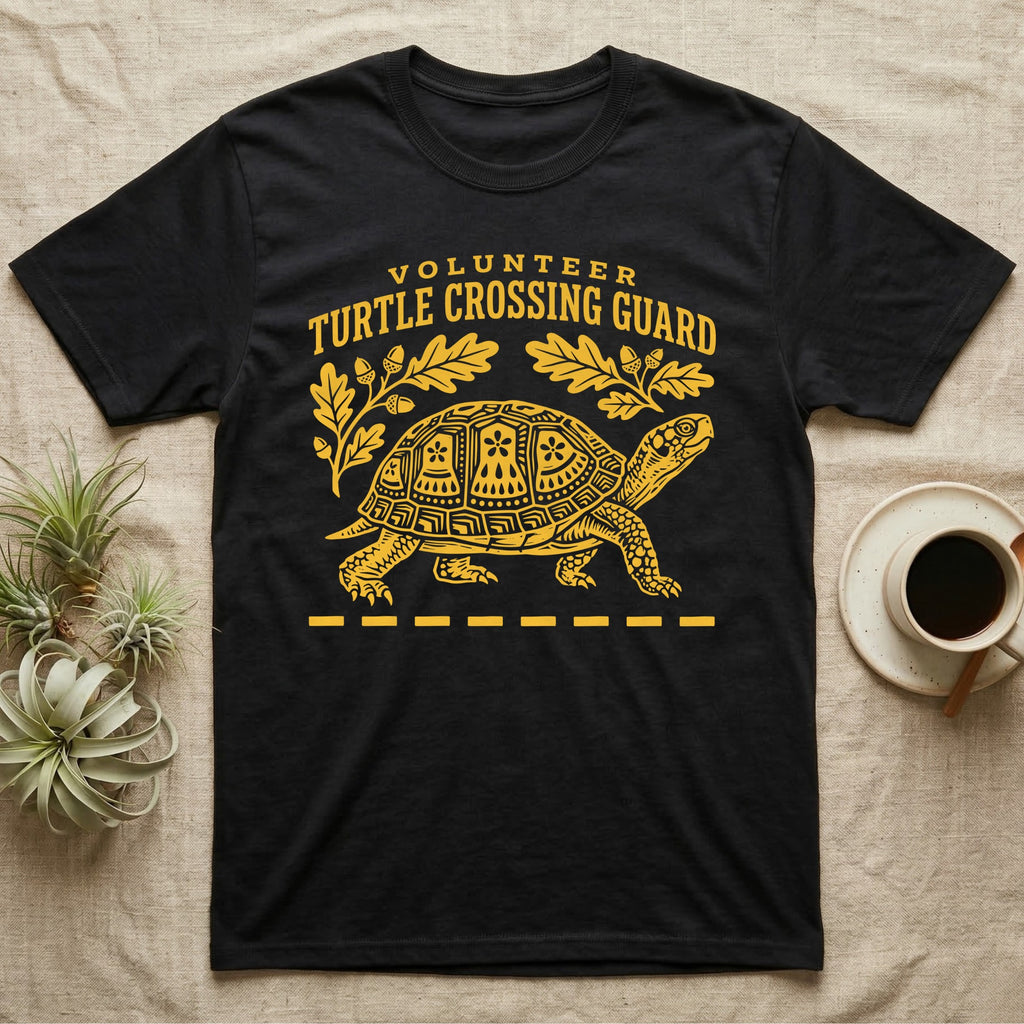 Box Turtle Crossing T-Shirt in Black — Yellow folk-print eastern box turtle walking across a dashed road line with oak leaves, text Volunteer Turtle Crossing Guard