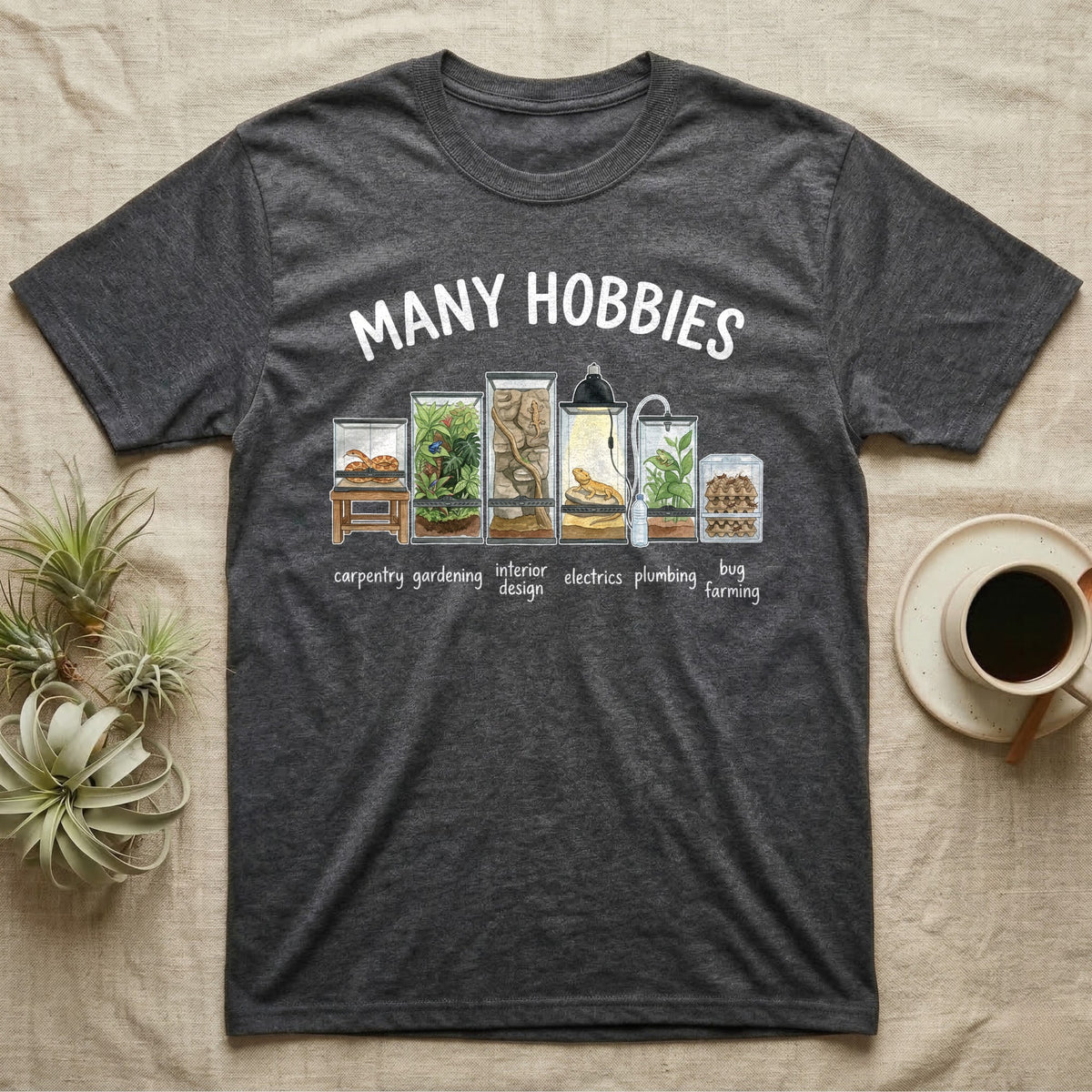 Reptile Terrarium Hobbies T-Shirt in Dark Heather — Watercolour row of reptile vivariums with a snake, dart frog, gecko, bearded dragon, tree frog and a cricket bin under MANY HOBBIES, each labelled carpentry to bug farming