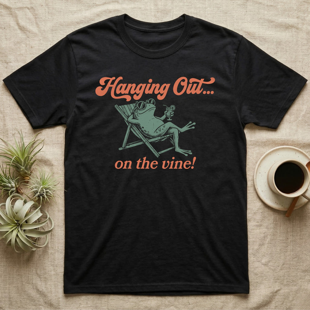 Tomato Frog Vine Vibes T-Shirt in Black — Illustrated tomato frog reclining in a beach chair with sunglasses and a cocktail, coral script reading Hanging Out On The Vine.