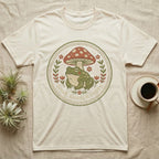Cream t-shirt with embroidered frog and mushroom design, reading "Small, Damp, & Happy".