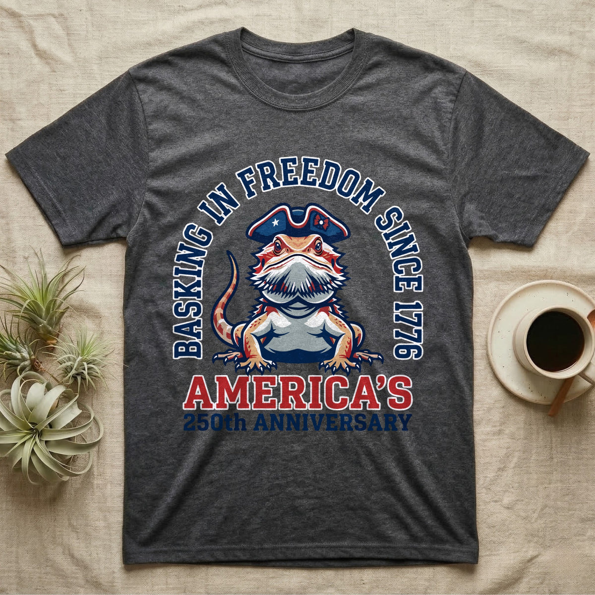 Bearded Dragon Basking T-Shirt in Dark Heather — Sports-logo bearded dragon in a tricorn hat under a collegiate arch reading Basking in Freedom Since 1776.
