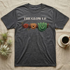 Green Tree Python Glow-Up T-Shirt in Dark Heather — Impasto illustration of a green tree python at three life stages on one branch: red hatchling, orange-brown subadult, green adult.
