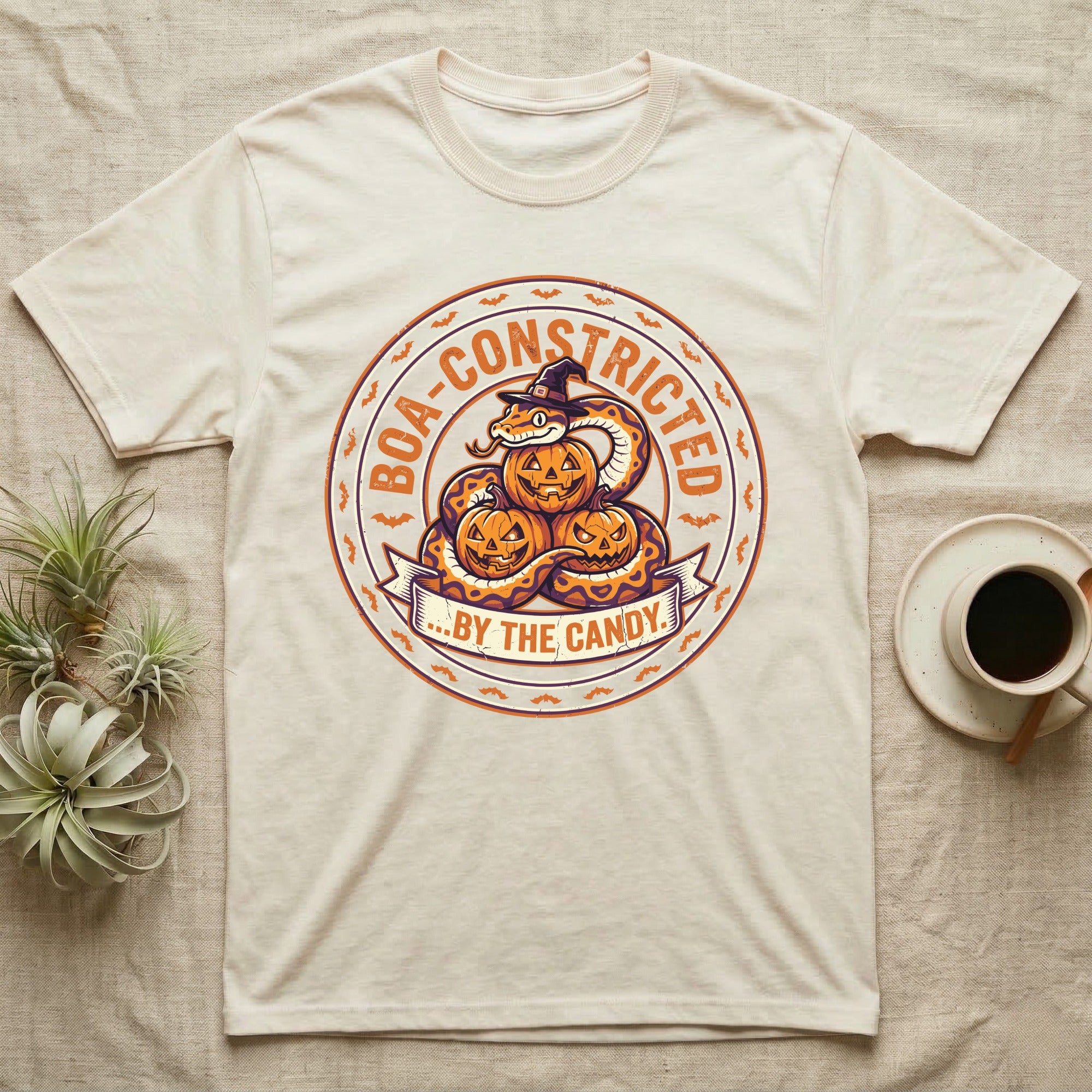 Ball Python Boa-Constricted Candy T-Shirt in Natural — Distressed badge of a witch-hatted ball python on three jack-o'-lanterns, "Boa-Constricted by the Candy."