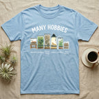 Reptile Terrarium Hobbies T-Shirt in Light Blue — Watercolour row of reptile vivariums with a snake, dart frog, gecko, bearded dragon, tree frog and a cricket bin under MANY HOBBIES, each labelled carpentry to bug farming