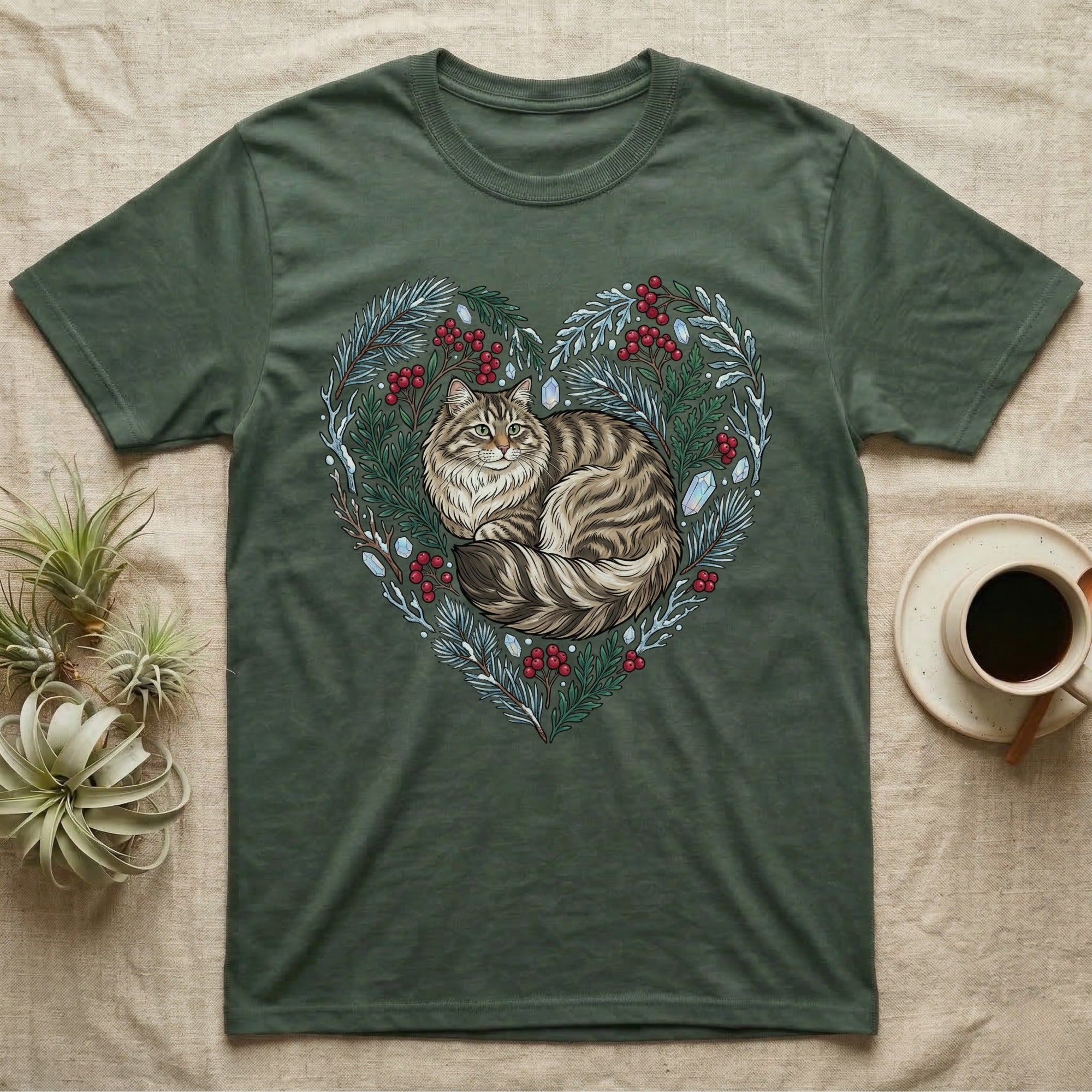 Green t-shirt featuring a cat curled within a heart-shaped wreath of berries and ice.