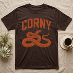 Corn Snake Corny T-Shirt in Dark Chocolate — Worn orange one-ink print of a corn snake lying in loose coils, head raised, under the arched word Corny