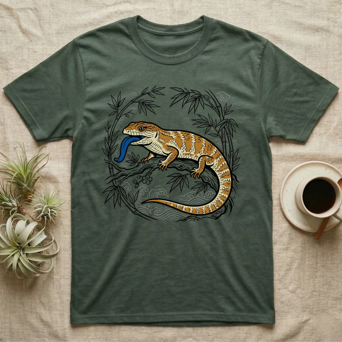 Bearded dragon with blue tongue on bamboo branch, dark green t-shirt.