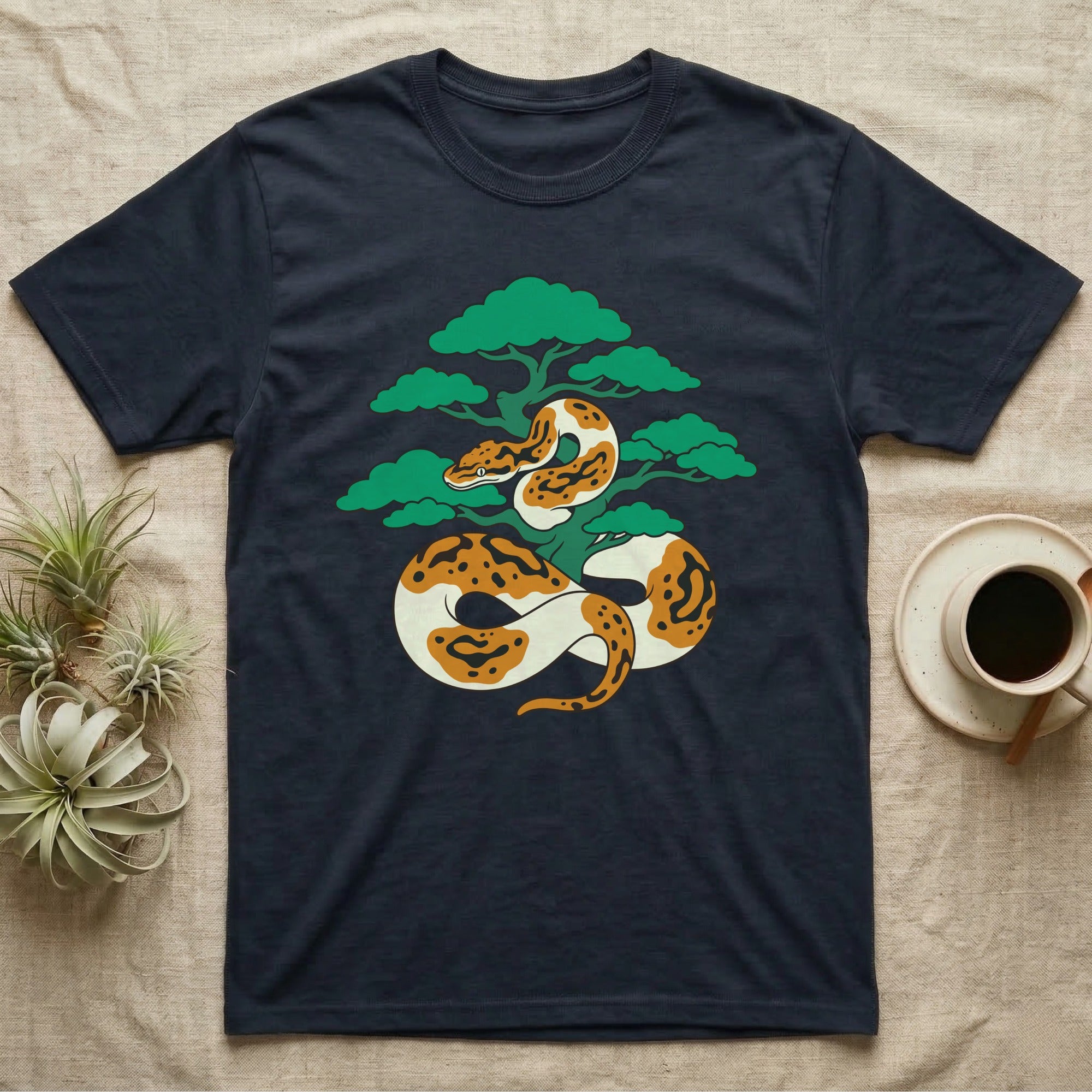 Dark t-shirt featuring a coiled orange and white snake around a green tree.