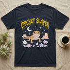 Leopard Gecko Feral T-Shirt in Navy — Smiling leopard gecko in a pastel desert-night scene under a spiky golden metal wordmark reading CRICKET SLAYER.