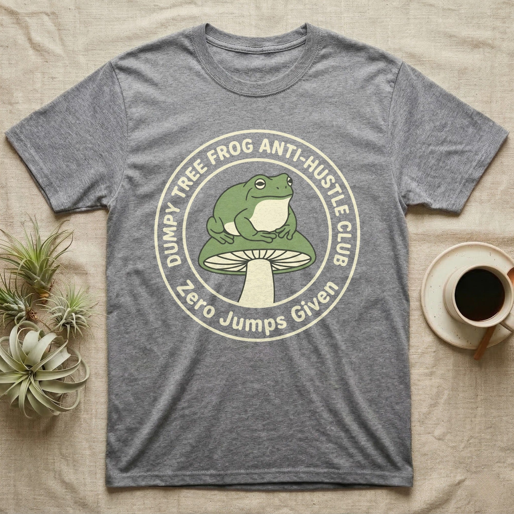 Grey t-shirt with "DUMPY TREE FROG ANTI-HUSTLE CLUB" text and a frog on a mushroom.