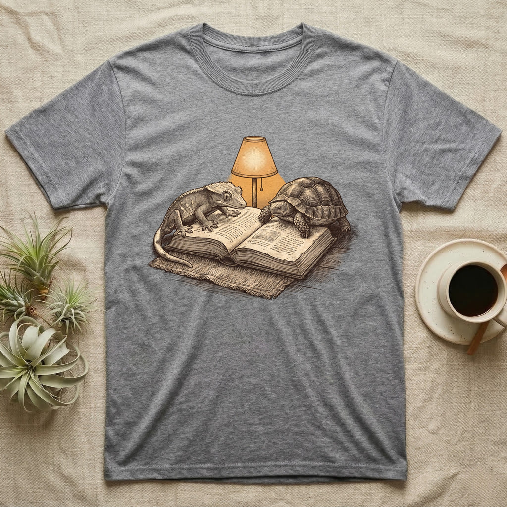 Cold-Blooded Book Club T-Shirt in Sport Grey — Engraved cozy illustration of a gecko and a tortoise sharing an open book under a glowing reading lamp.