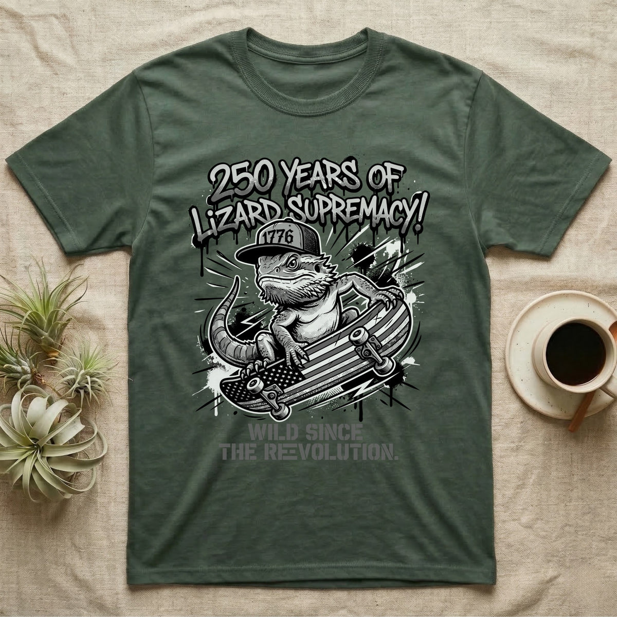 Bearded Dragon Skater T-Shirt in Military Green — Black-and-white bearded dragon in a 1776 snapback on a flag skateboard under text 250 Years of Lizard Supremacy.