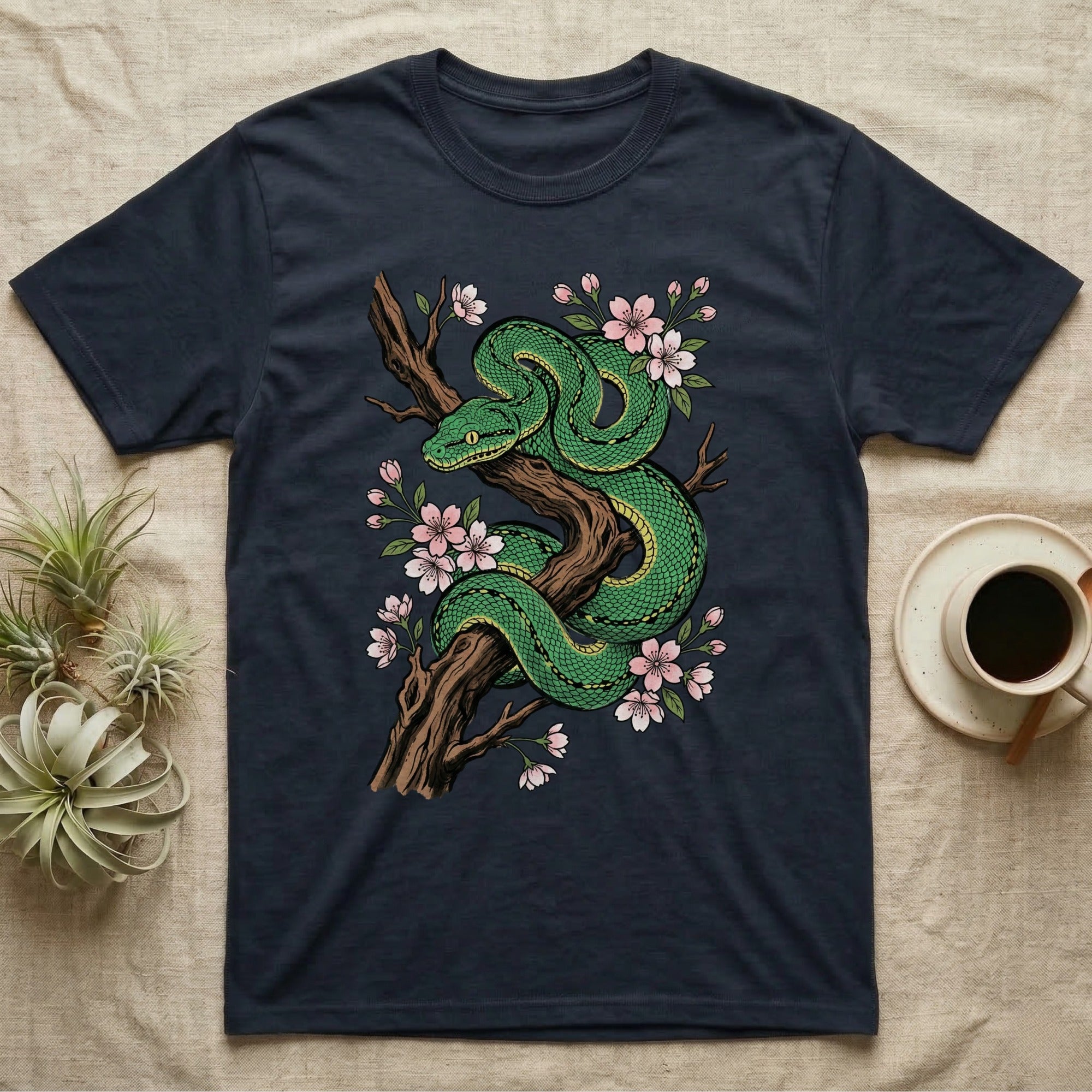 Green coiled snake with pink cherry blossoms on a dark t-shirt.
