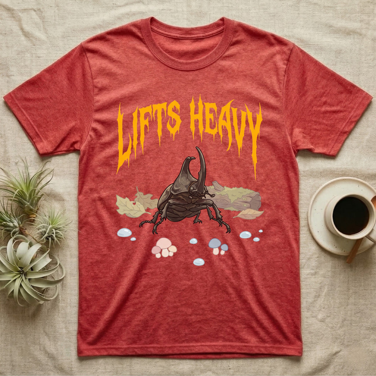 Rhino Beetle Feral T-Shirt in Heather Red — Horned rhinoceros beetle standing head-on below a dripping amber-gold metal "Lifts Heavy" wordmark