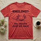 Axolotl Resting Face T-Shirt in Heather Red — Engraved axolotl sitting head-on with gills fanned and a wide smile, with the words Smiling? No, That's Just My Face