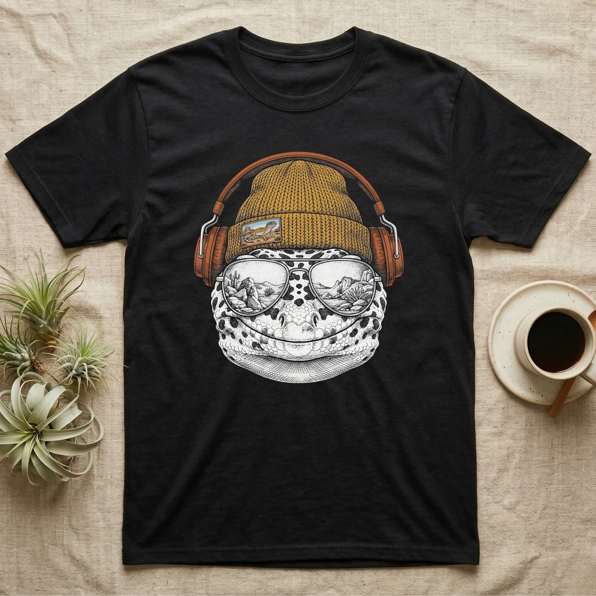 Leopard Gecko Headphones T-Shirt in Black — Engraved leopard gecko with spotted skin in a beanie and headphones, aviators reflecting a desert canyon.