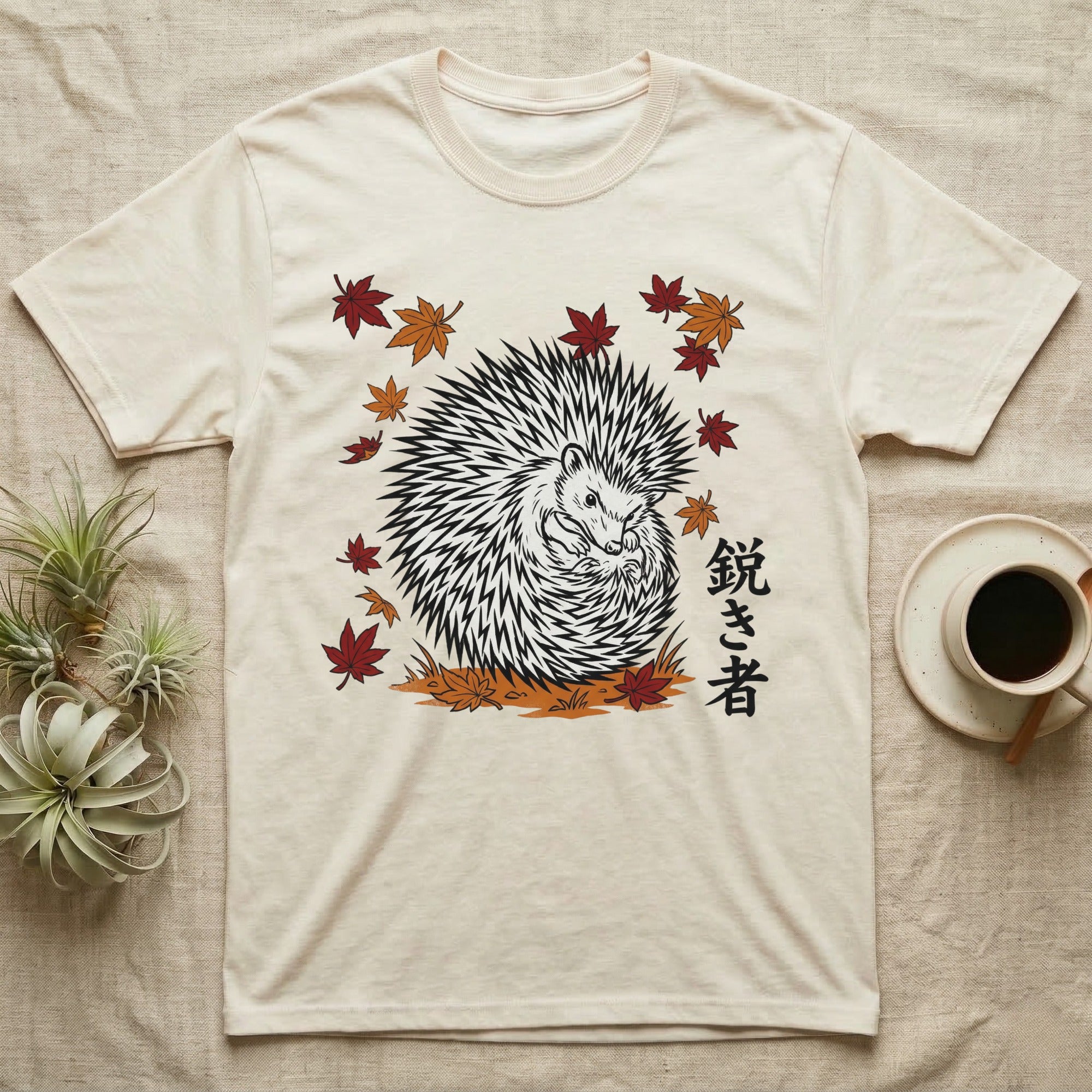 Cream t-shirt with a black and white hedgehog illustration surrounded by falling leaves.