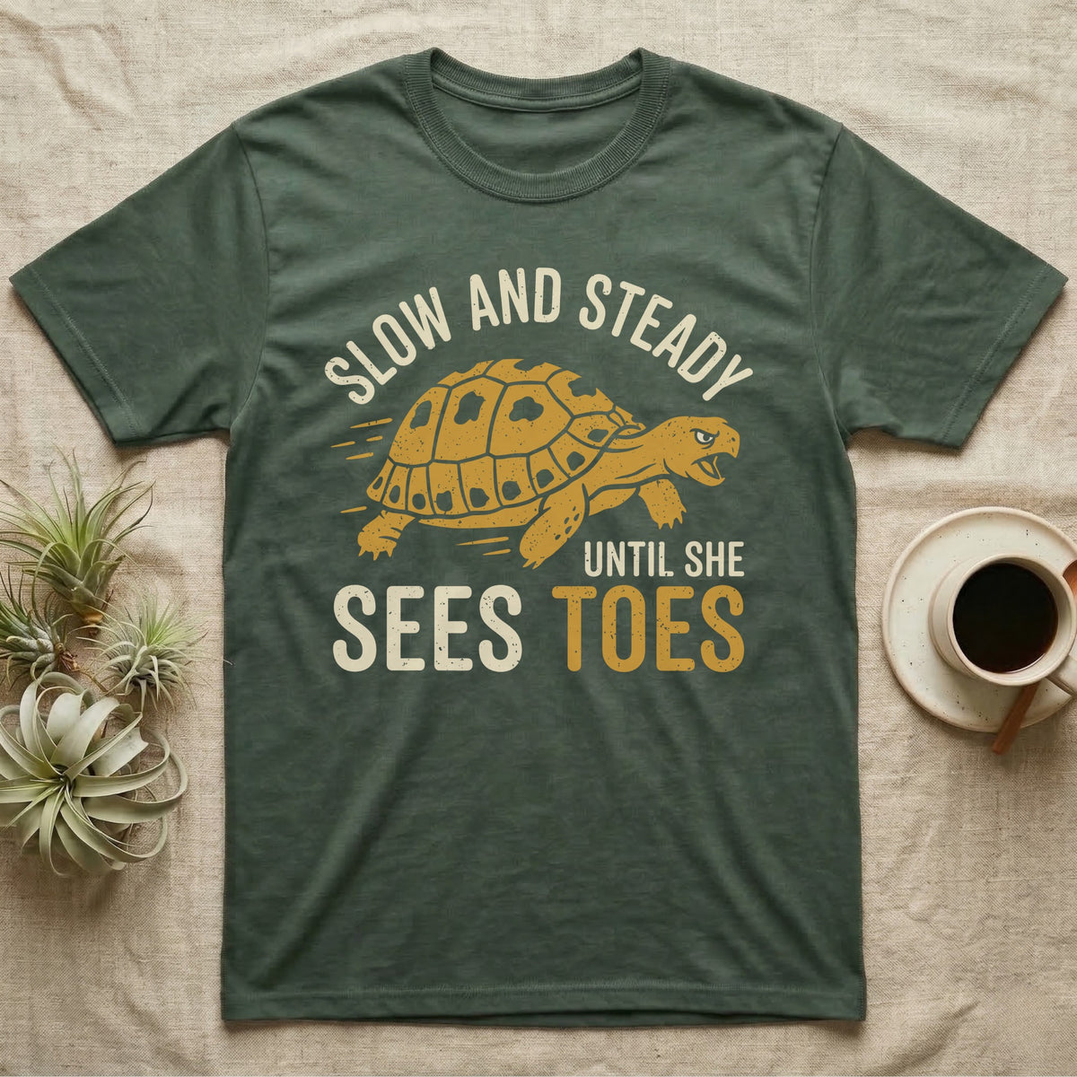 Hermann's Tortoise Toes T-Shirt in Military Green — Golden ochre Hermann's tortoise charging to the right under arched cream words Slow And Steady, with Until She Sees Toes below