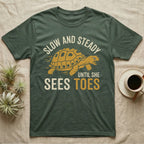 Hermann's Tortoise Toes T-Shirt in Military Green — Golden ochre Hermann's tortoise charging to the right under arched cream words Slow And Steady, with Until She Sees Toes below