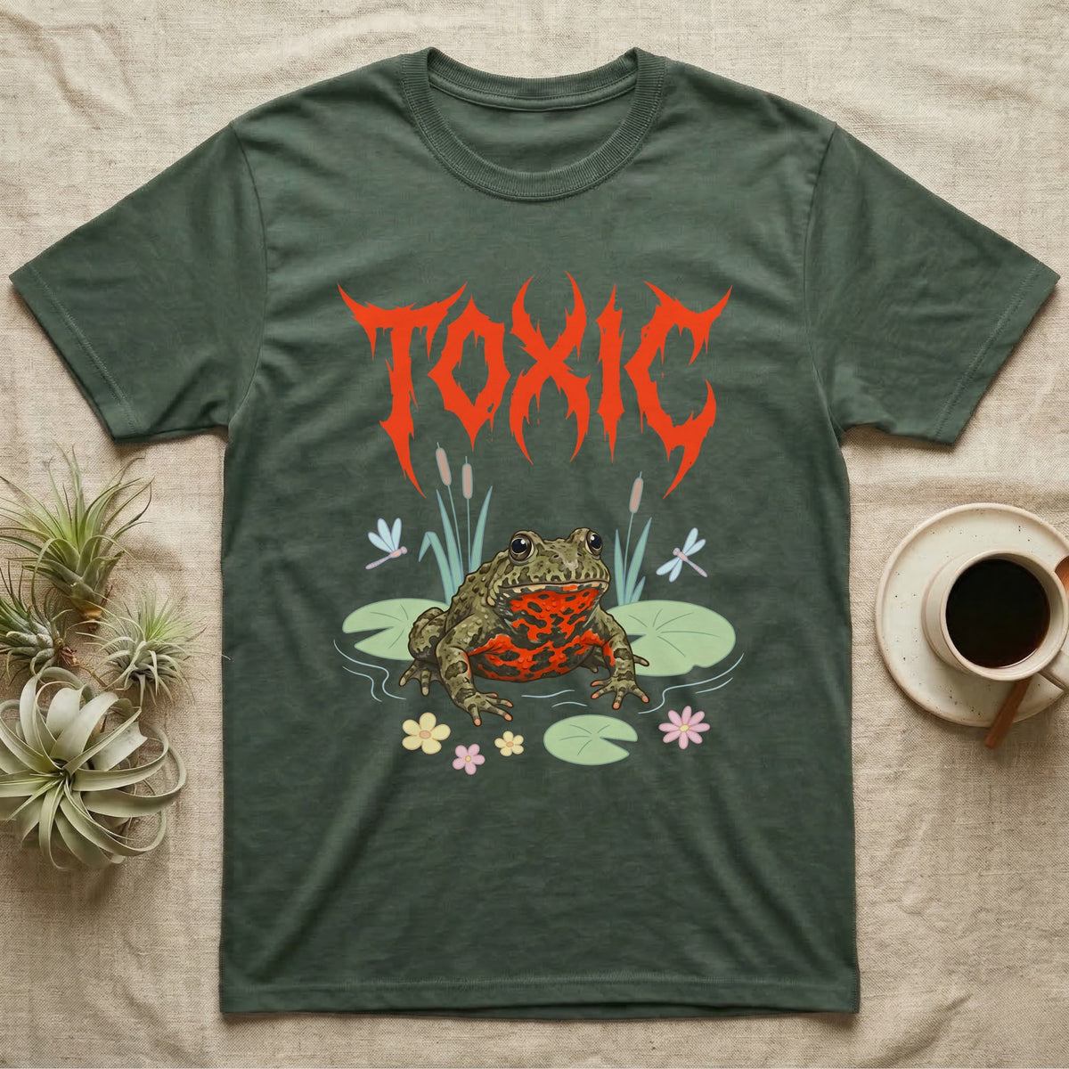 Oriental Fire-Bellied Toad Feral T-Shirt in Military Green — Pastel fire-bellied toad with red-orange belly among lily pads and dragonflies, jagged metal wordmark "TOXIC" above.