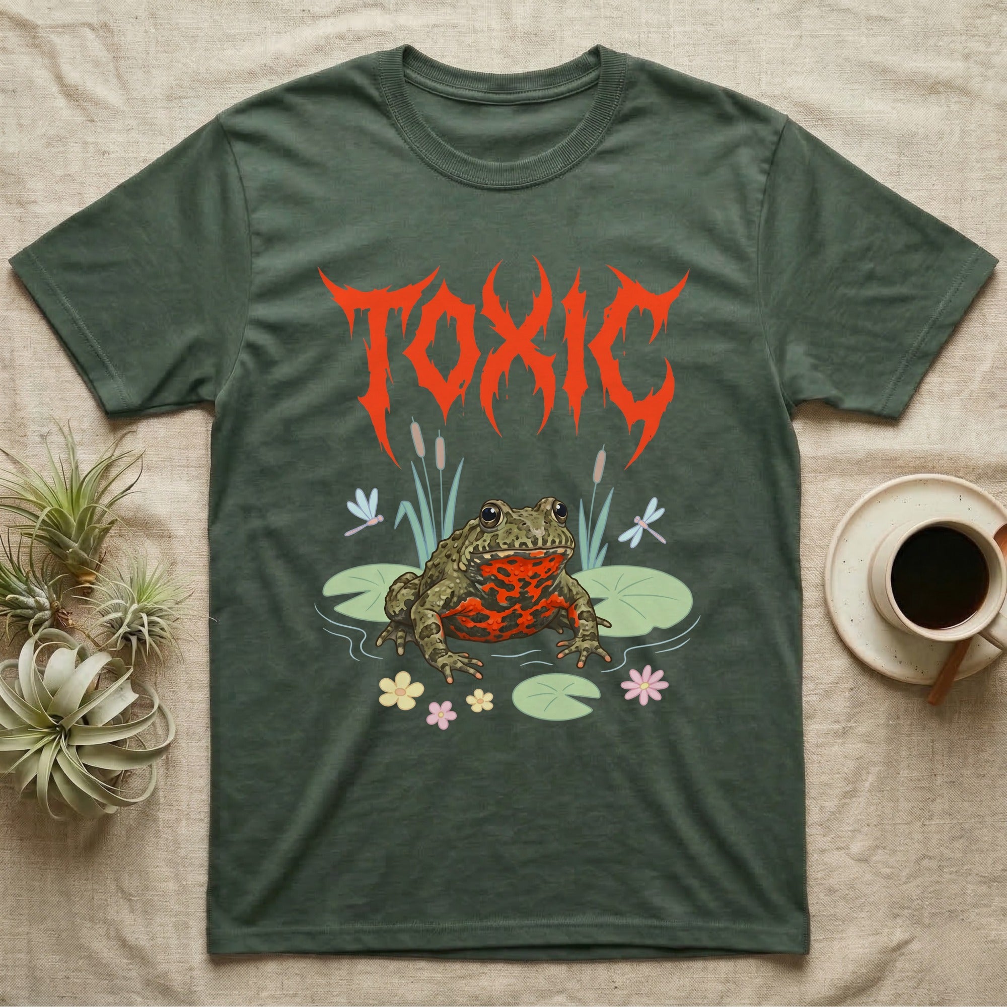 Oriental Fire-Bellied Toad Feral T-Shirt in Military Green — Pastel fire-bellied toad with red-orange belly among lily pads and dragonflies, jagged metal wordmark "TOXIC" above.