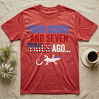 Gecko Four Score T-Shirt in Heather Red — Block text Four Score and Seven Tails Ago with a flag-filled word above a white gecko silhouette shedding its tail.