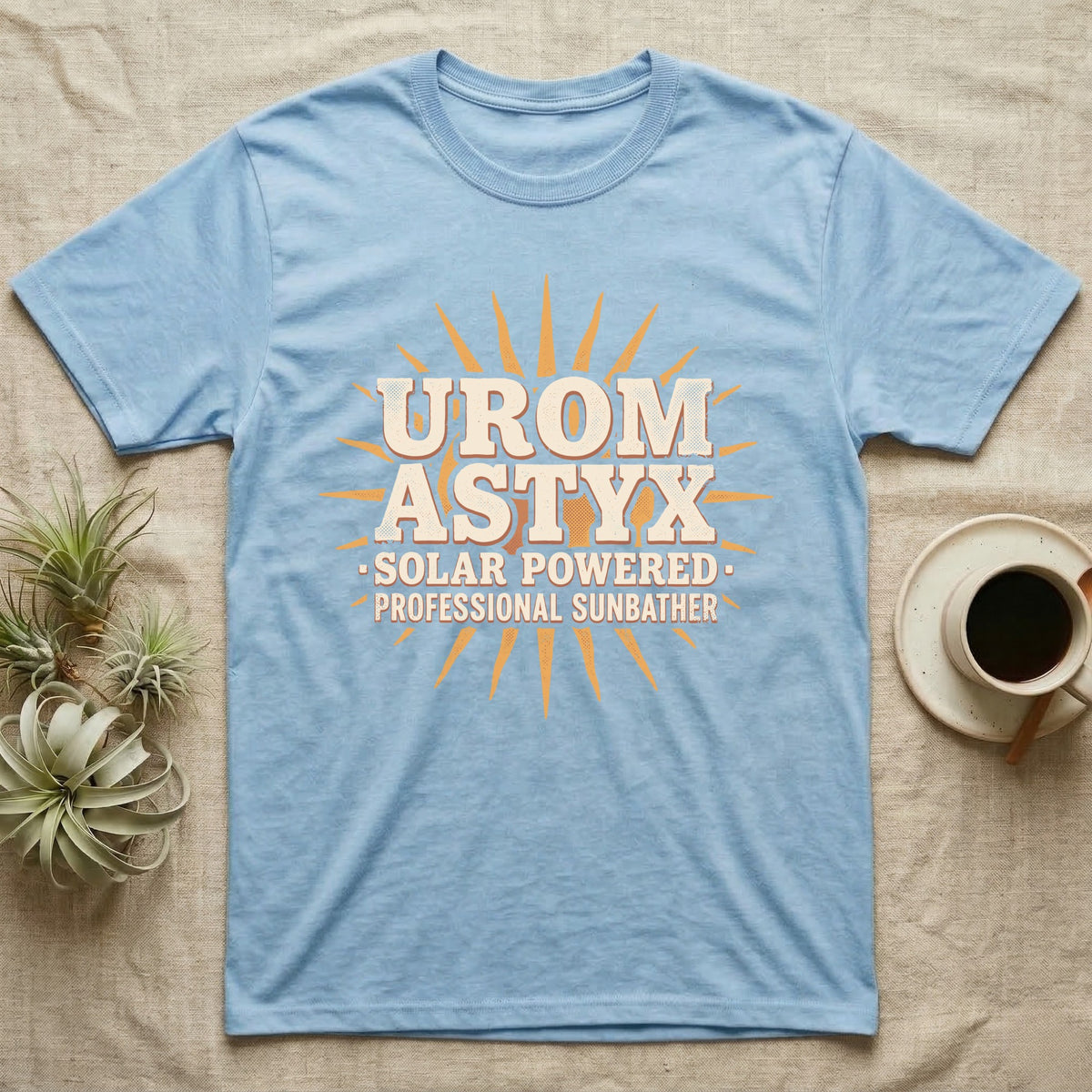 Solar Powered Uromastyx T-Shirt in Light Blue — Desert-poster wordmark reading "Uromastyx Solar Powered Professional Sunbather" with a small radiating sun motif.