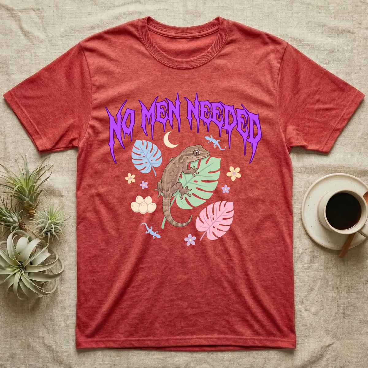 Mourning Gecko Feral T-Shirt in Heather Red — Mourning gecko on a leaf flanked by clone silhouettes under a jagged violet metal "NO MEN NEEDED" wordmark.