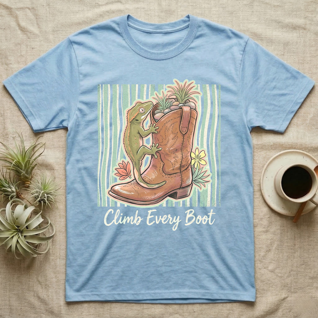 Light blue t-shirt with a gecko climbing a cowboy boot, text reads "Climb Every Boot."