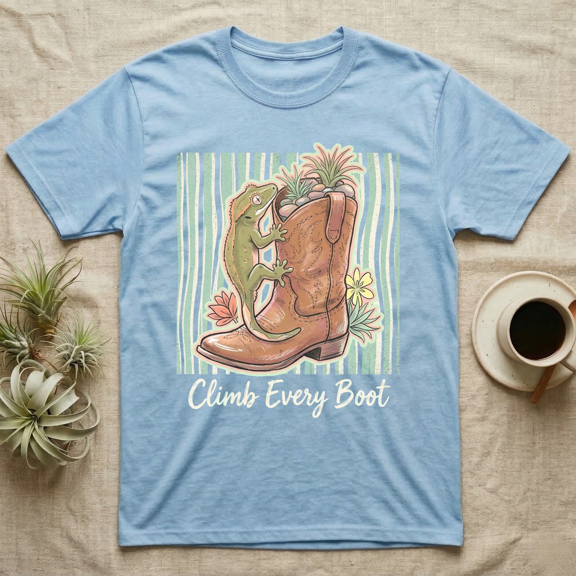 Light blue t-shirt with a gecko climbing a cowboy boot, text reads "Climb Every Boot."