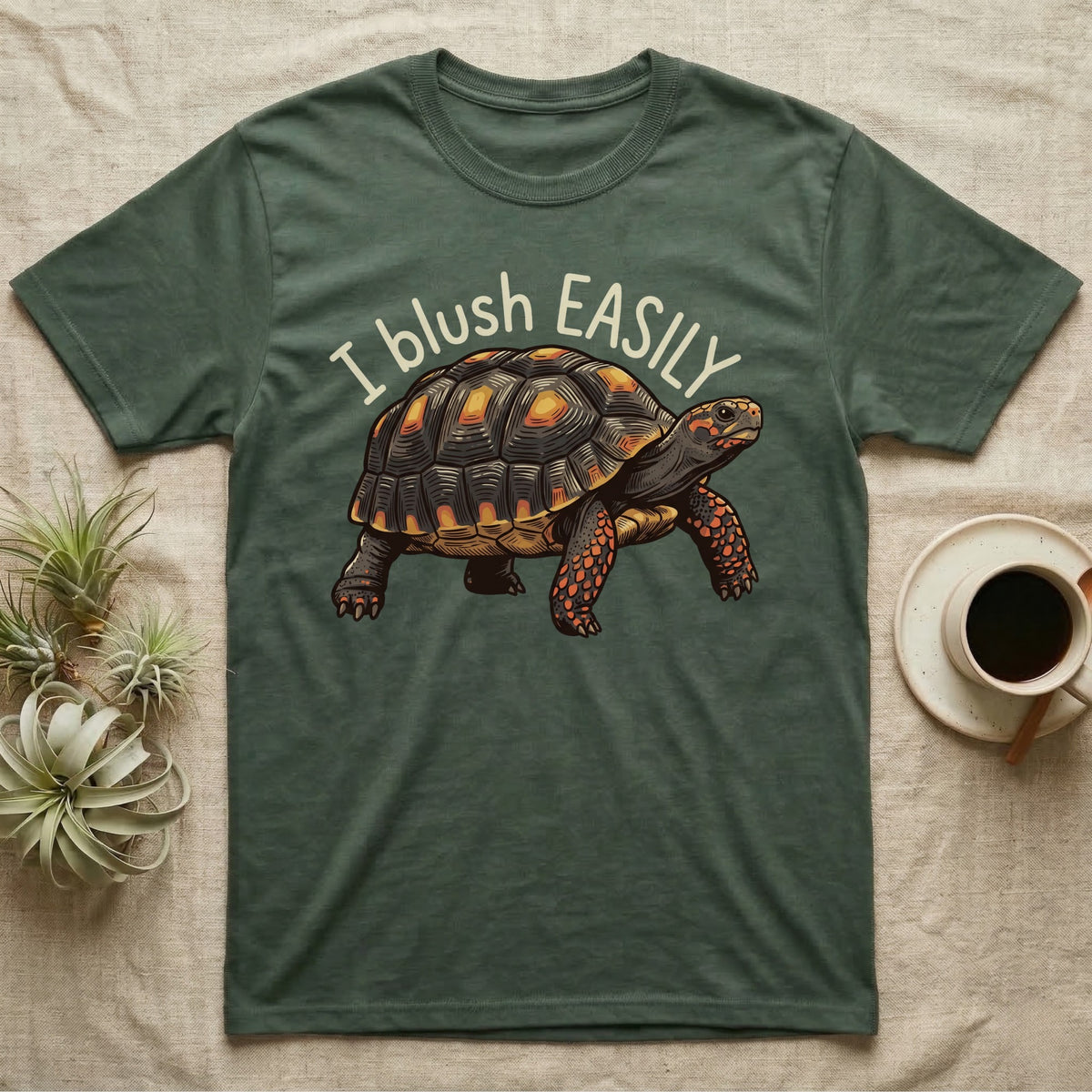 Red-Foot Tortoise Blush T-Shirt in Military Green — Red-footed tortoise with red-orange cheeks and legs walking under the curved words I blush EASILY