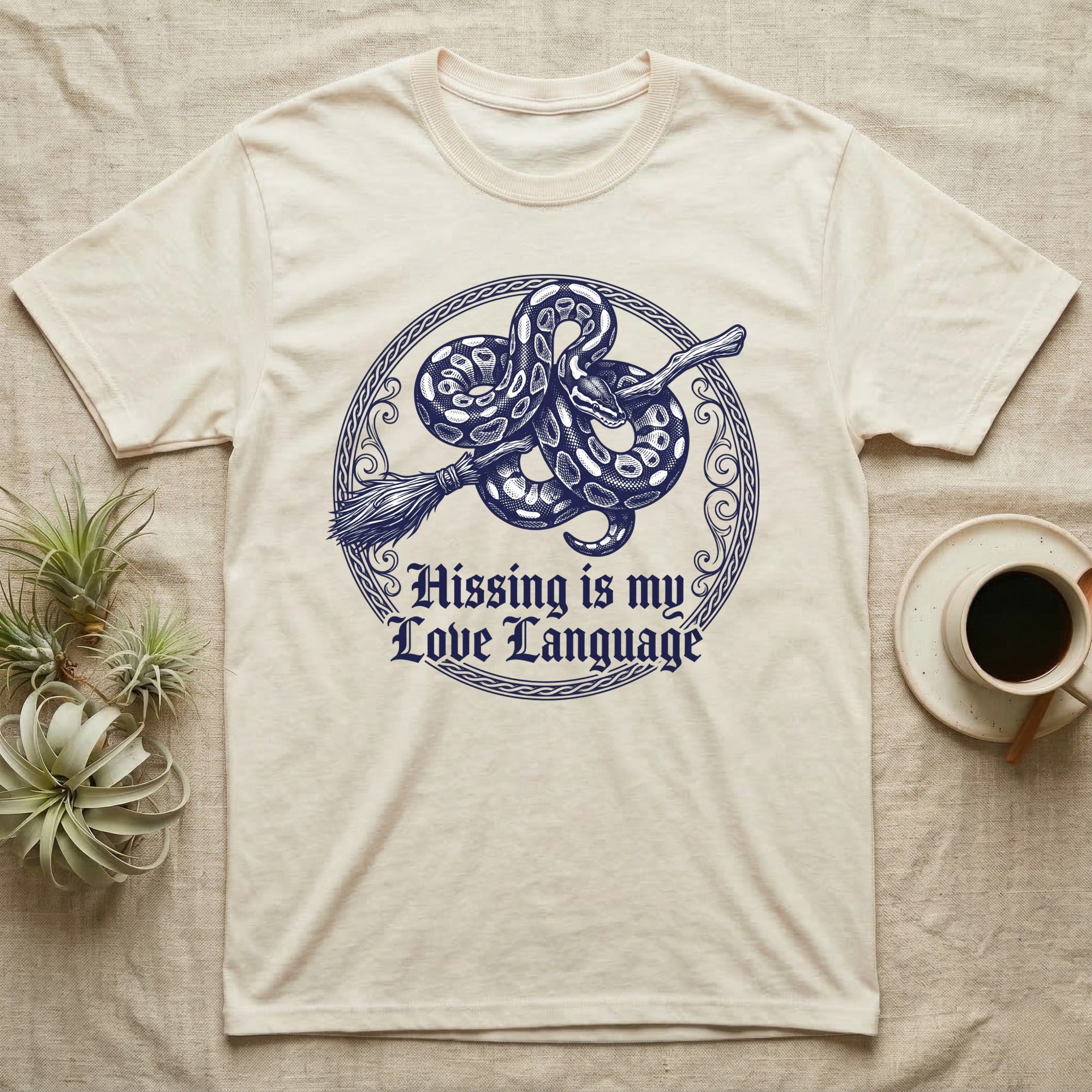 Ball Python Hissing Love Language T-Shirt in Natural — Navy engraving of a ball python coiled around a broomstick in a knotwork ring, "Hissing Is My Love Language."