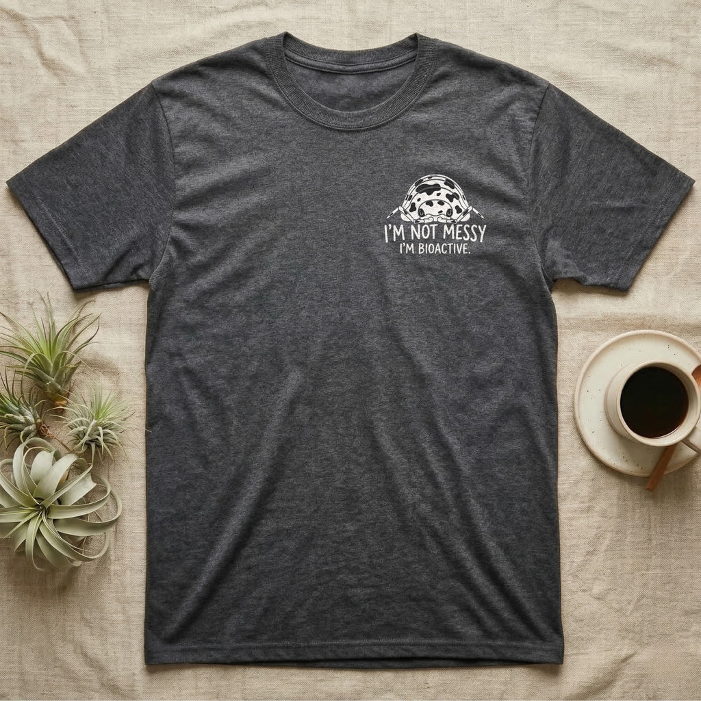 Bioactive Dairy Cow T-Shirt in Dark Heather — White dairy cow isopod with black cow patches peeking over white marker capitals reading I'M NOT MESSY I'M BIOACTIVE.