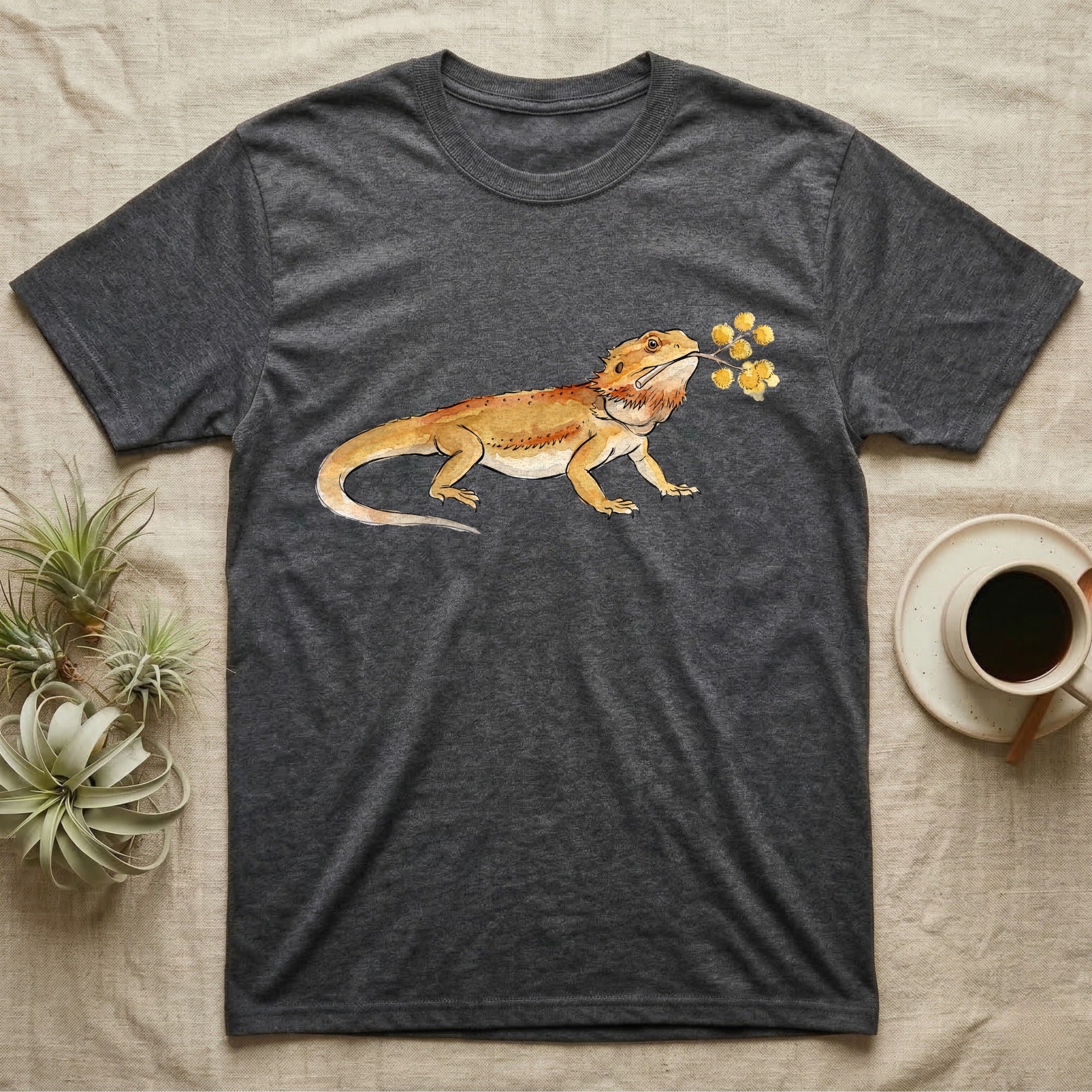 Bearded Dragon Blossom T-Shirt in Dark Heather — Watercolor illustration of an ochre bearded dragon holding a golden wattle blossom sprig, on a dark grey t-shirt.