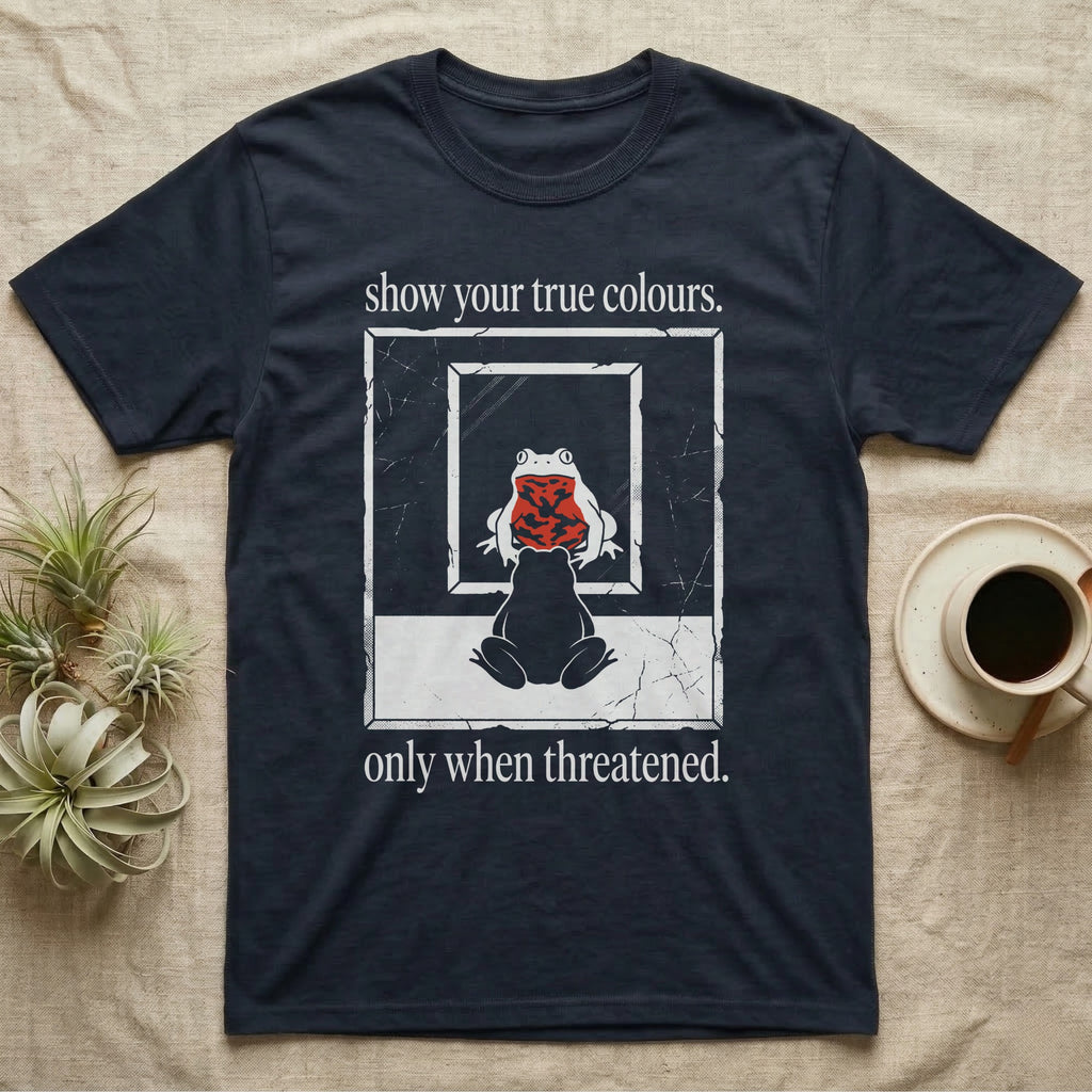 Fire-Bellied Toad Mirror T-Shirt in Navy — Worn photocopy-style poster of a fire-bellied toad seen from behind looking into a mirror, its reflection showing a bright red marbled belly, with the words show your true colours, only when threatened.