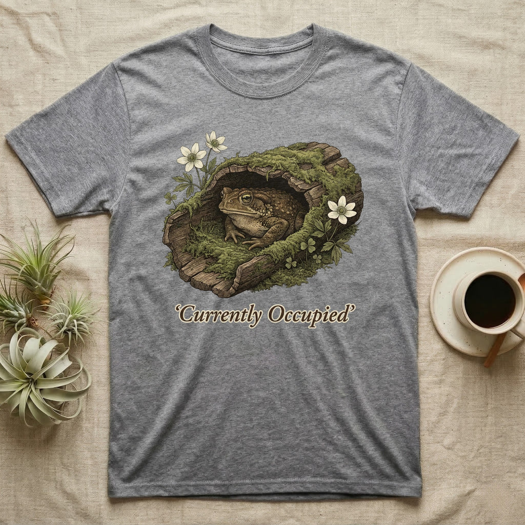Grey t-shirt with frog in mossy log graphic and text "Currently Occupied".