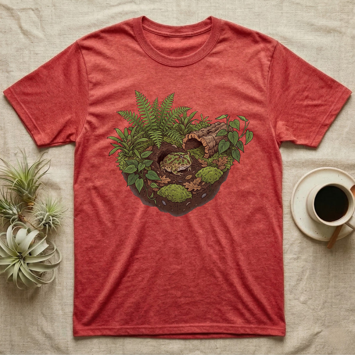 Pacman Frog Vivarium T-Shirt in Heather Red — Botanical illustration of a pacman frog thriving in a planted bioactive vivarium beside a small empty plastic cup.