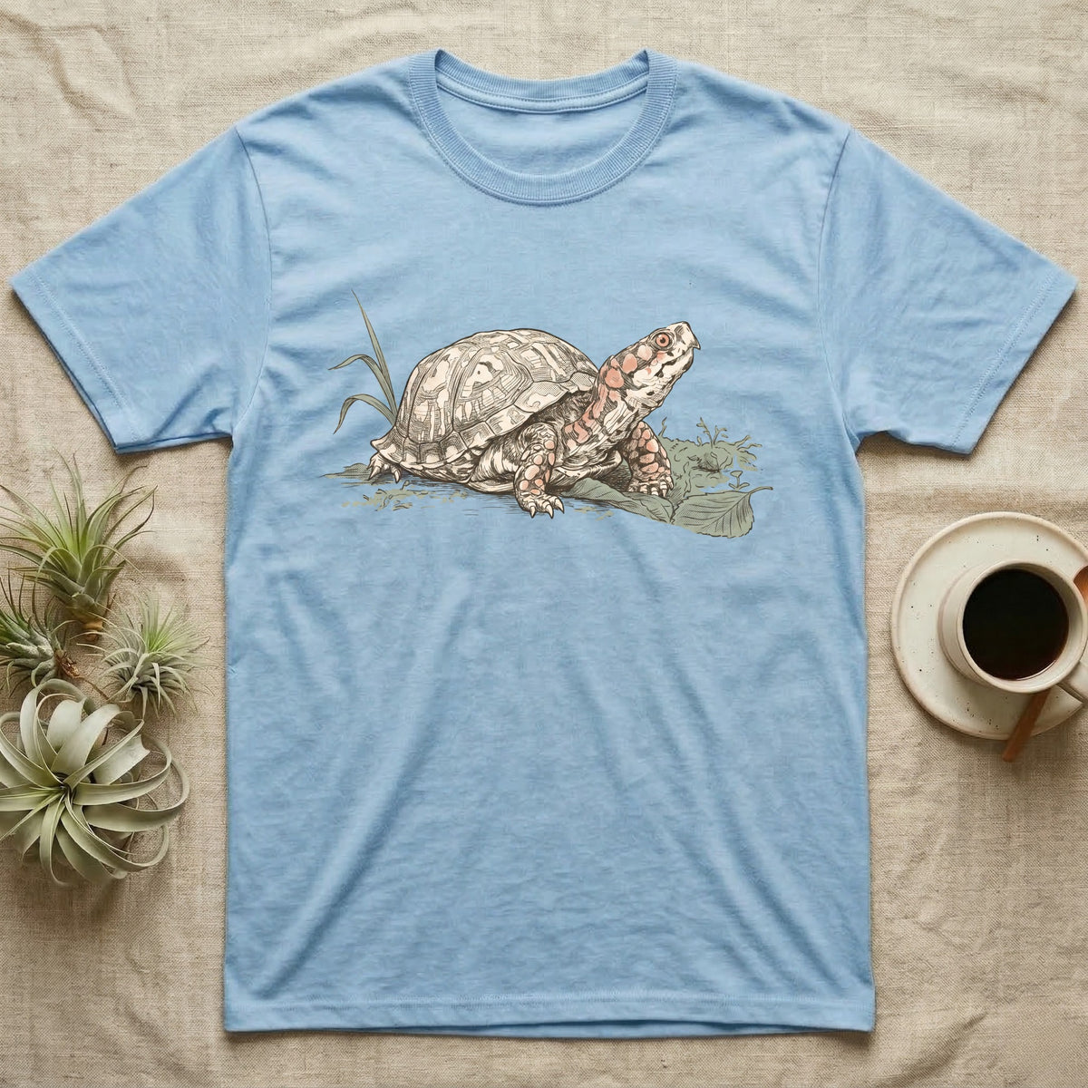 Box Turtle Shell T-Shirt in Light Blue — Naturalist-plate illustration of a box turtle with its shell shown as living body, above a serif welfare creed caption.