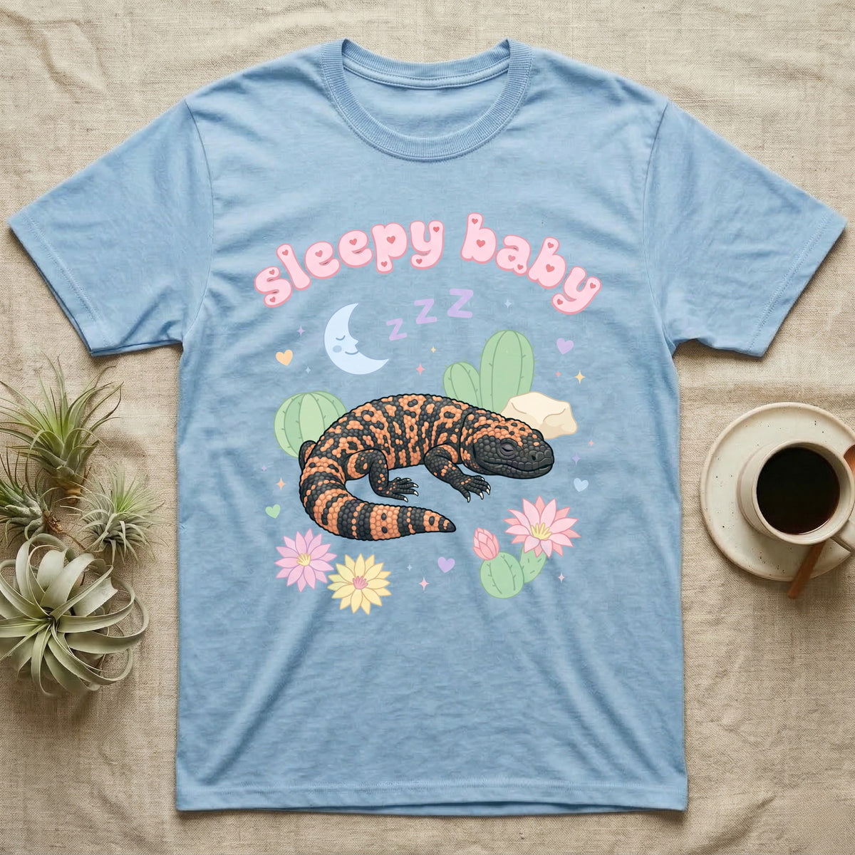 Gila Monster Baby T-Shirt in Light Blue — Pastel Gila monster with sleepy eyes, crescent moon and Z Z Z, puffy salmon bubble wordmark "sleepy baby" above.