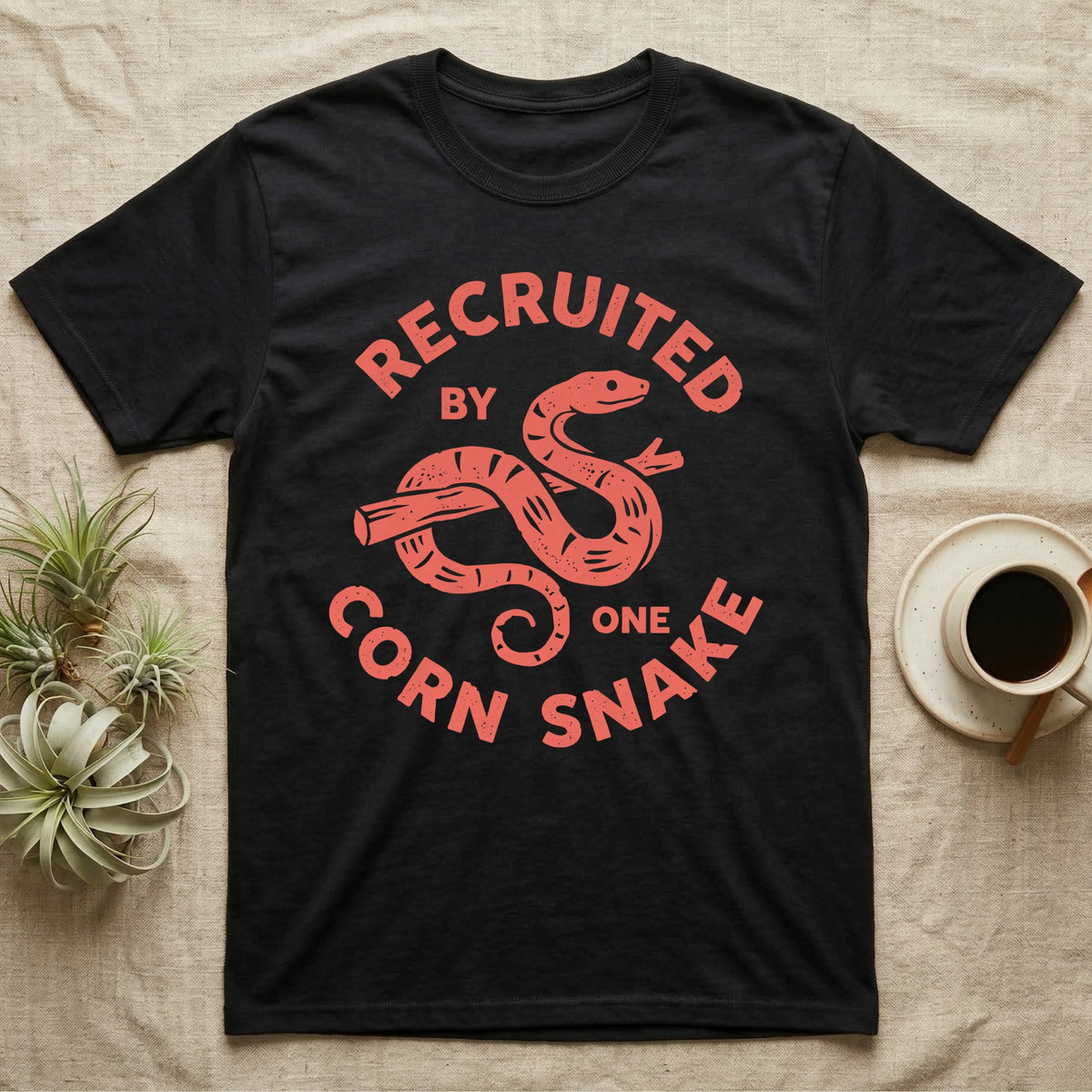 Corn Snake Recruit T-Shirt in Black — Hand-carved block-print badge of a corn snake on a branch inside ring lettering reading Recruited By One Corn Snake.