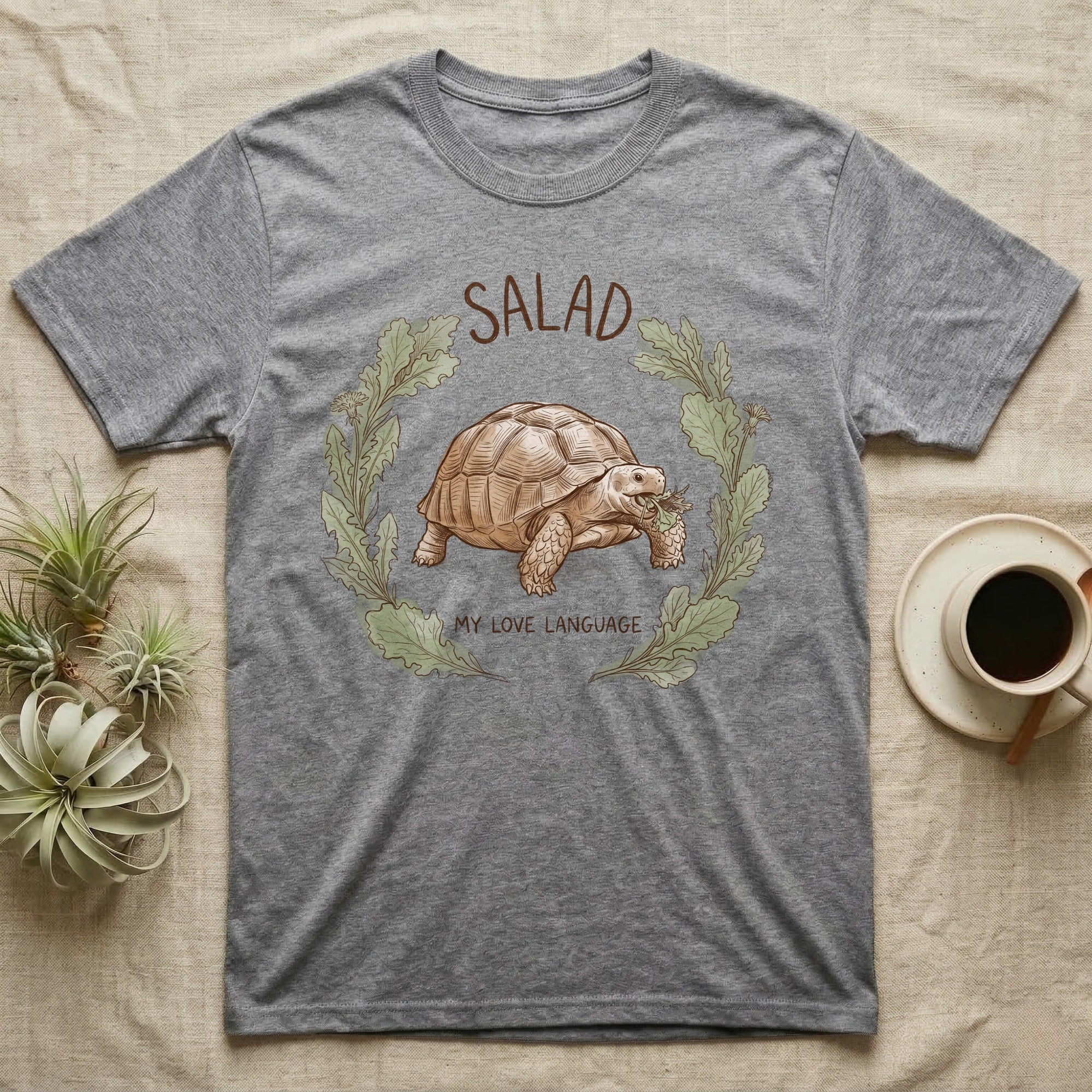 Sulcata Tortoise Salad Love T-Shirt in Sport Grey — Sepia watercolour illustration of a Sulcata tortoise mid-bite inside a salad-greens wreath with "SALAD" lettering.