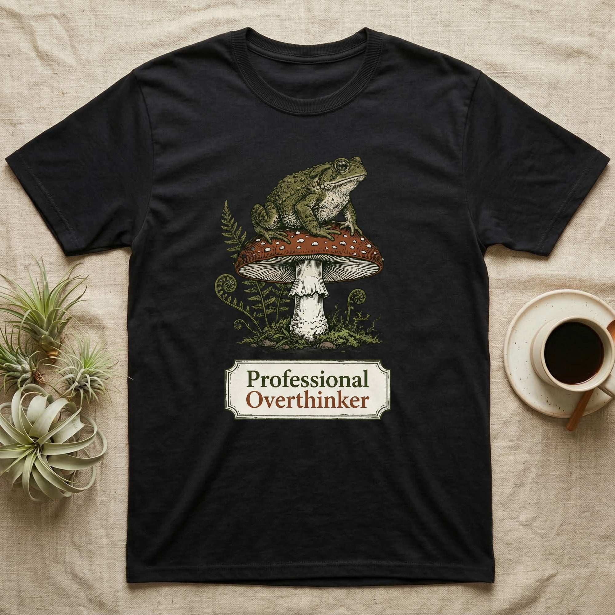 Black t-shirt with frog sitting on mushroom graphic and "Professional Overthinker" text.