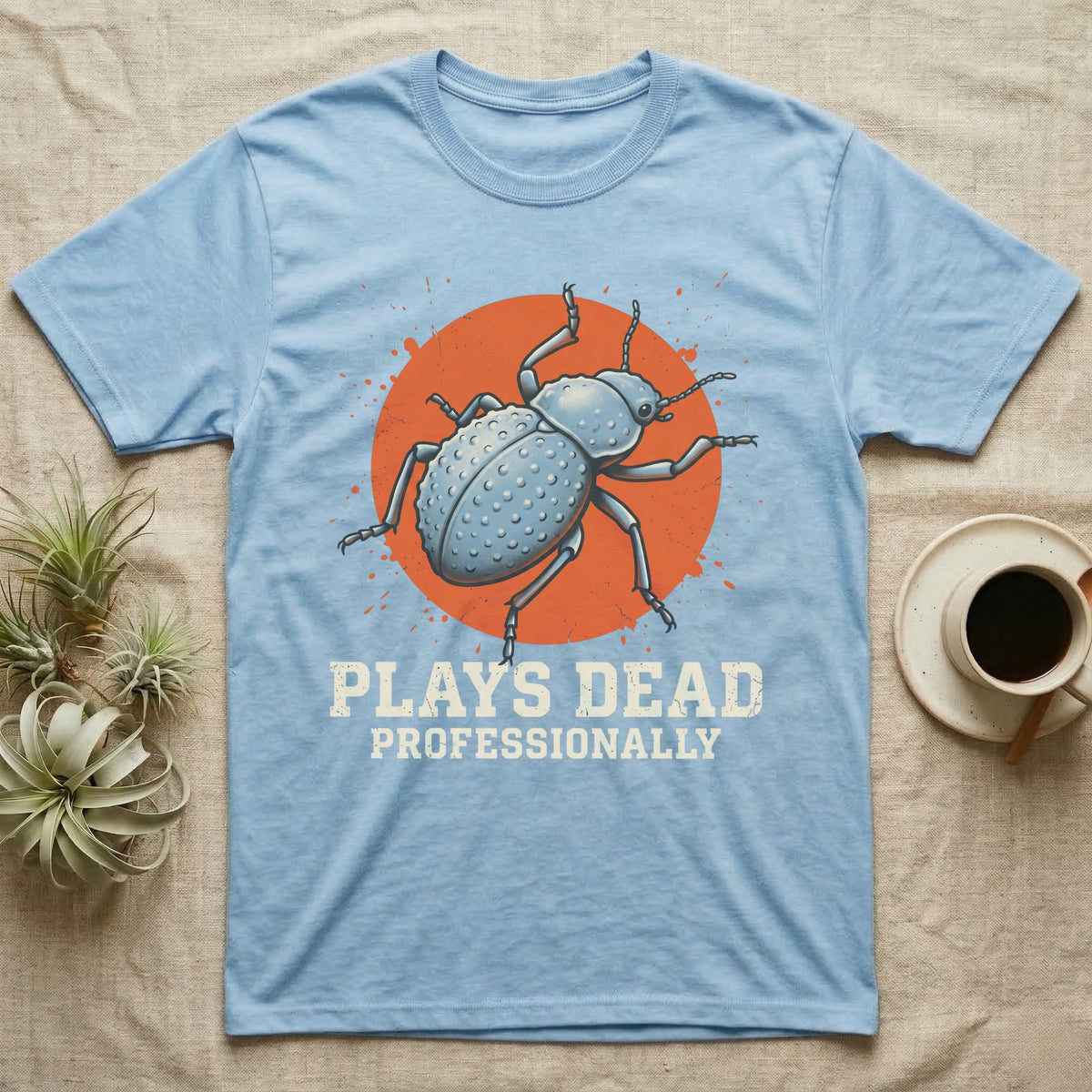 Blue Death Feigning Beetle T-Shirt in Light Blue — Distressed disc portrait of a blue death-feigning beetle over an orange circle with text plays dead