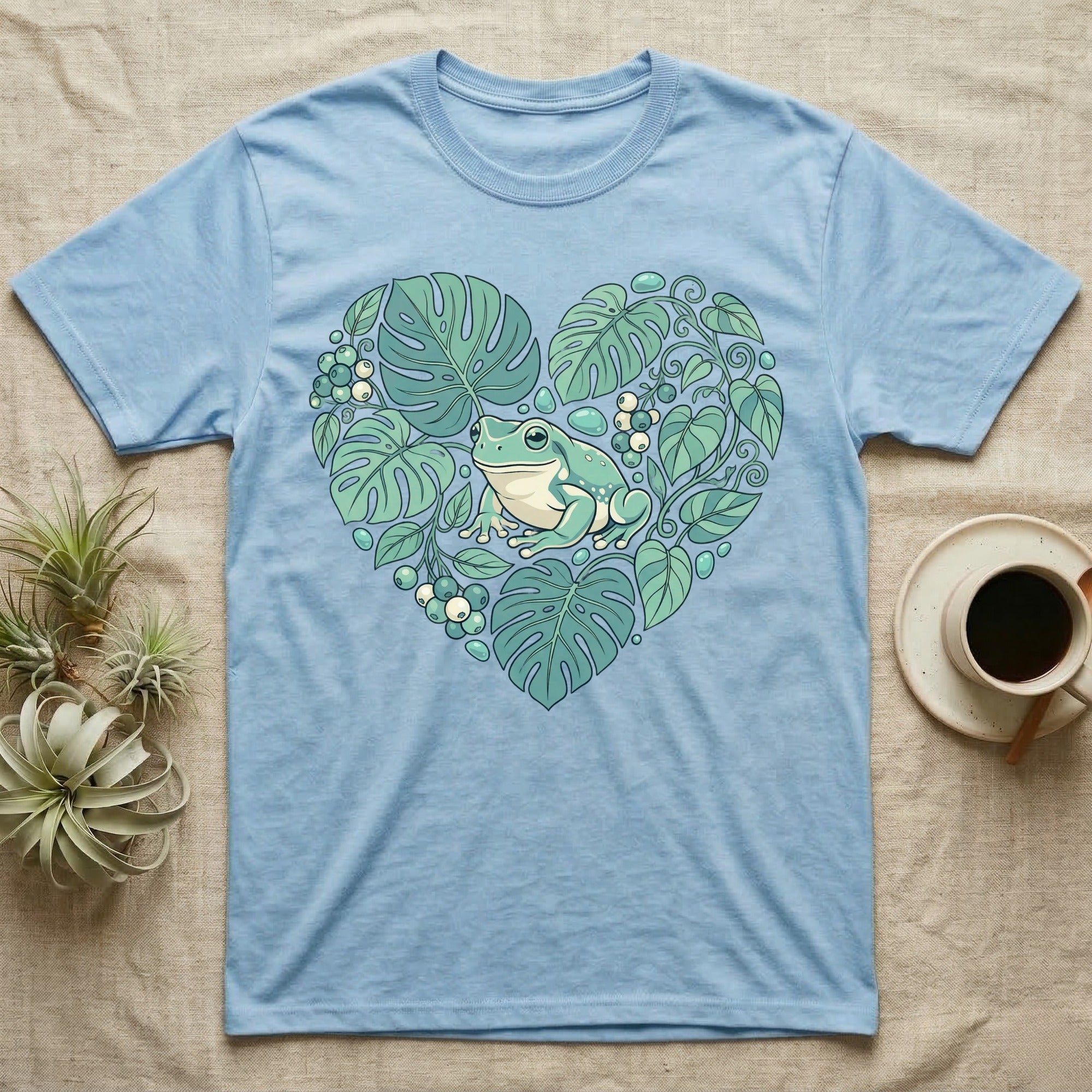 Blue t-shirt with a green frog in a heart-shaped arrangement of leaves.